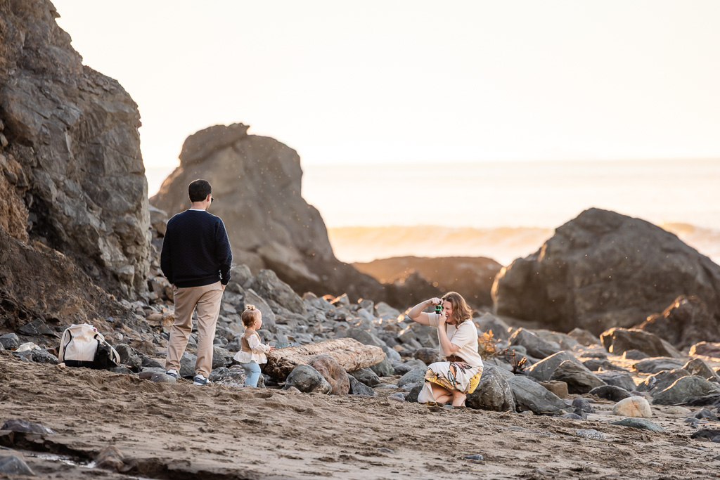 family taking photos of their baby on the beach