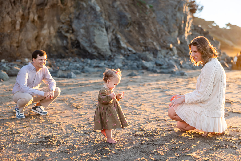 mom and dad with baby on the beach