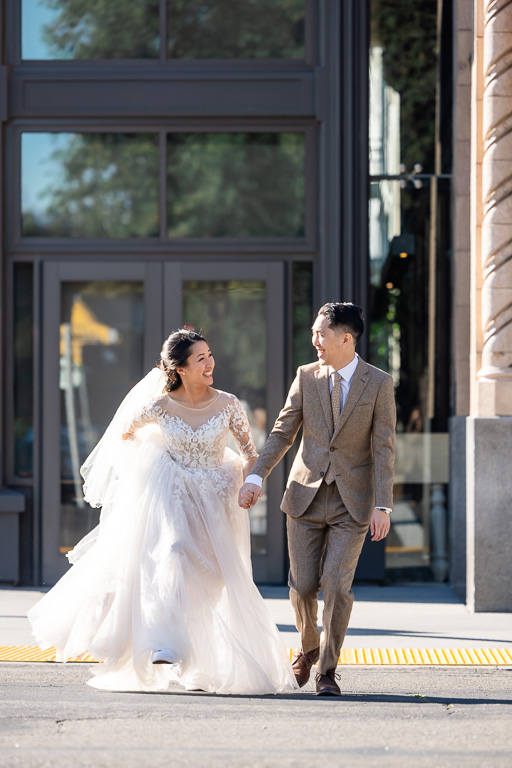 bride and groom happily running acroos the street at a crosswalk