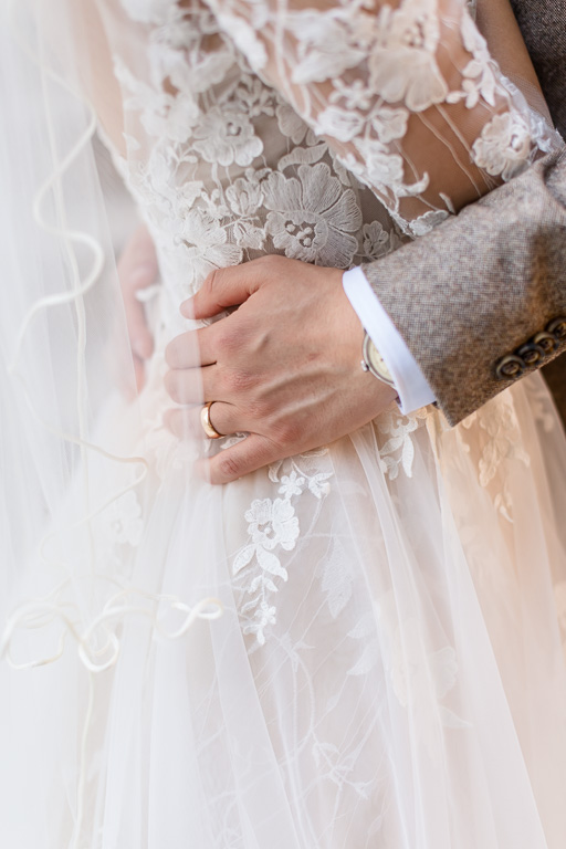 close-up of the groom's hands around the bride
