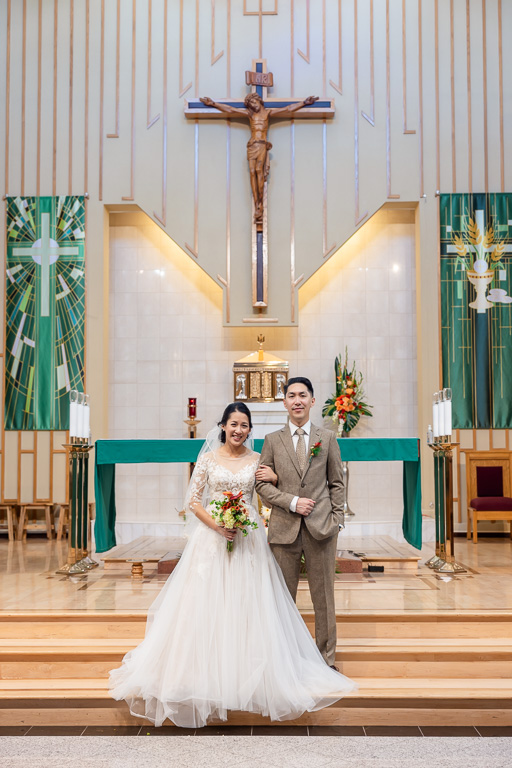 portrait of the bride and groom at the altar at Vietnamese Martyrs Church