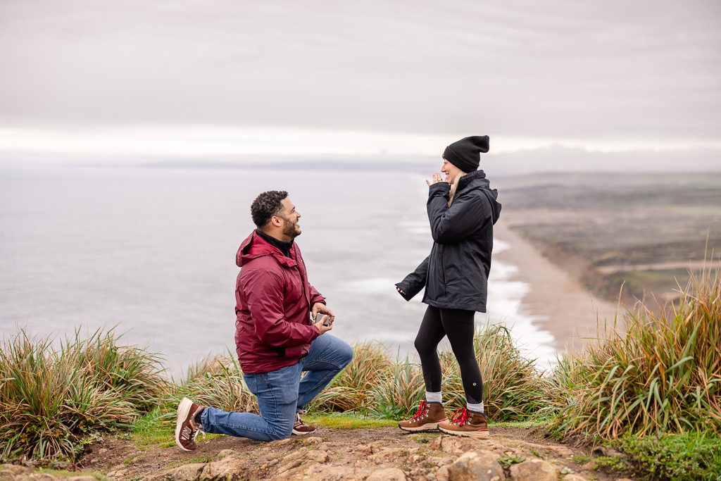 surprise marriage proposal at cliff overlook over endless beach