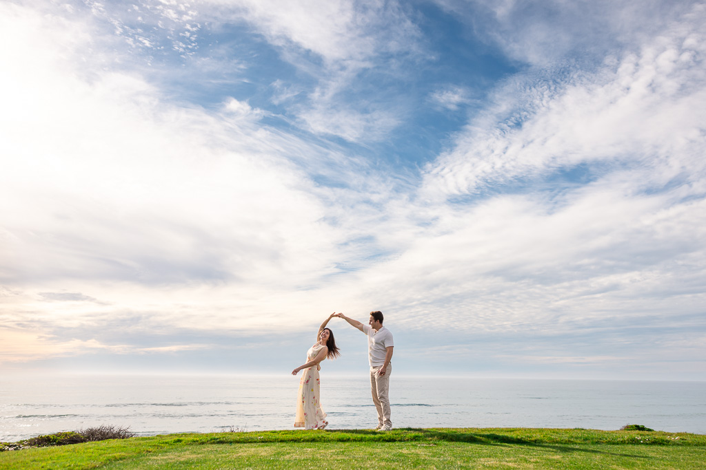 springtime engagement photos against a sunny blue sky and white clouds