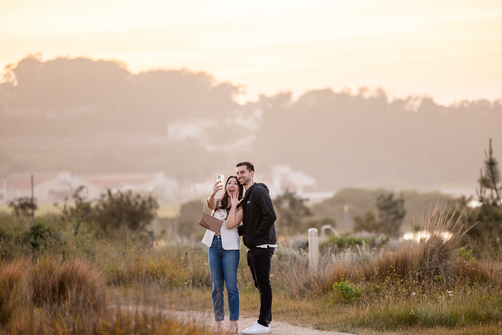 sneaky papparazzi photo of newly-engaged couple taking a selfie with the ring