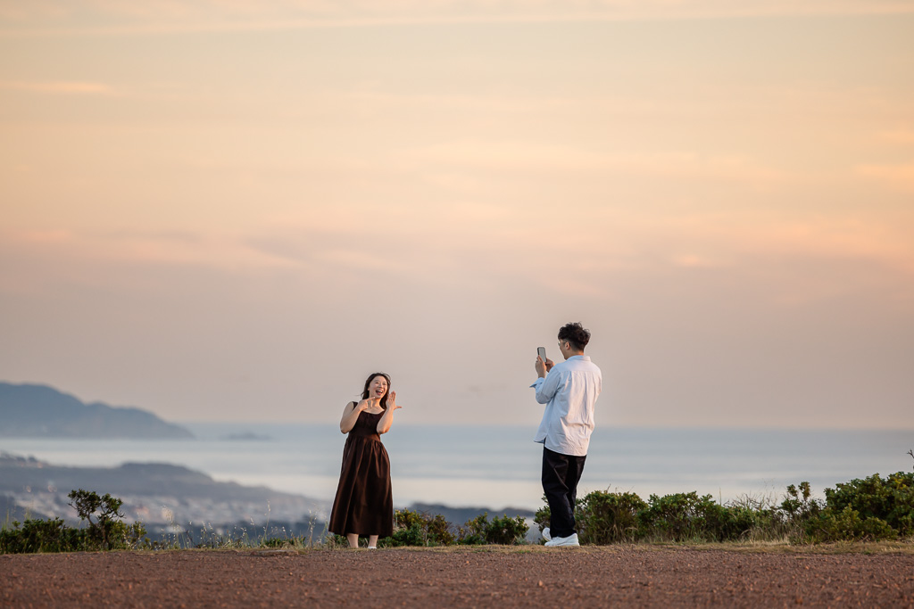 a sneaky paparazzi photo of couple taking iPhone photo of engagement ring