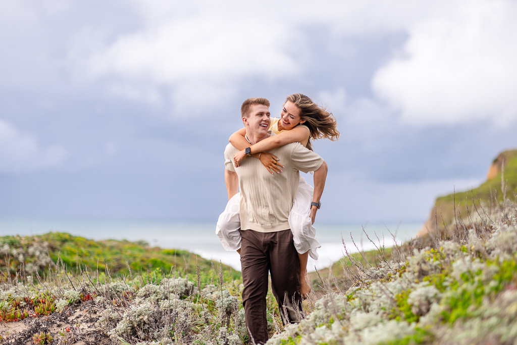 couple piggyback riding by the ocean