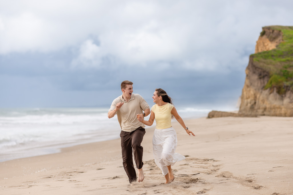 couple running along the shoreline on the beach