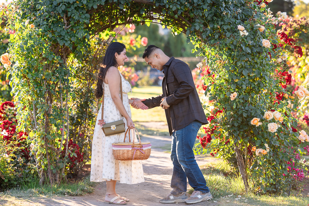 kneeling down to propose in front of a rose arch