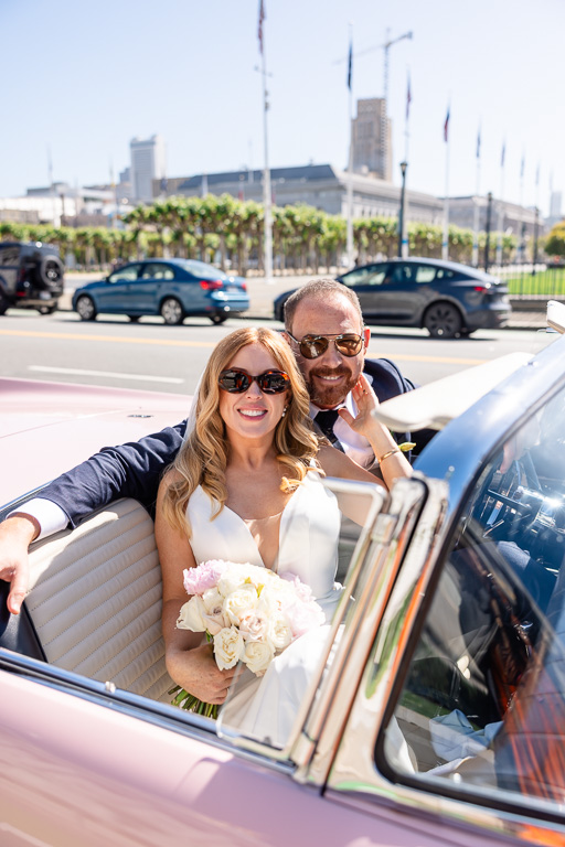 newlyweds sitting inside a pink Ford Thunderbird