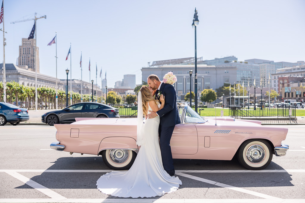 wedding photo with couple in front of a pink Thunderbird
