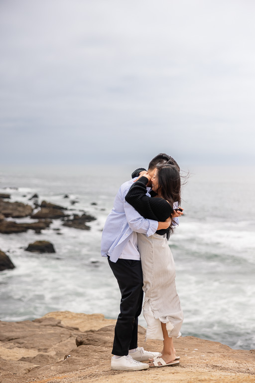 just-engaged couple hugging on a cliffside overlook