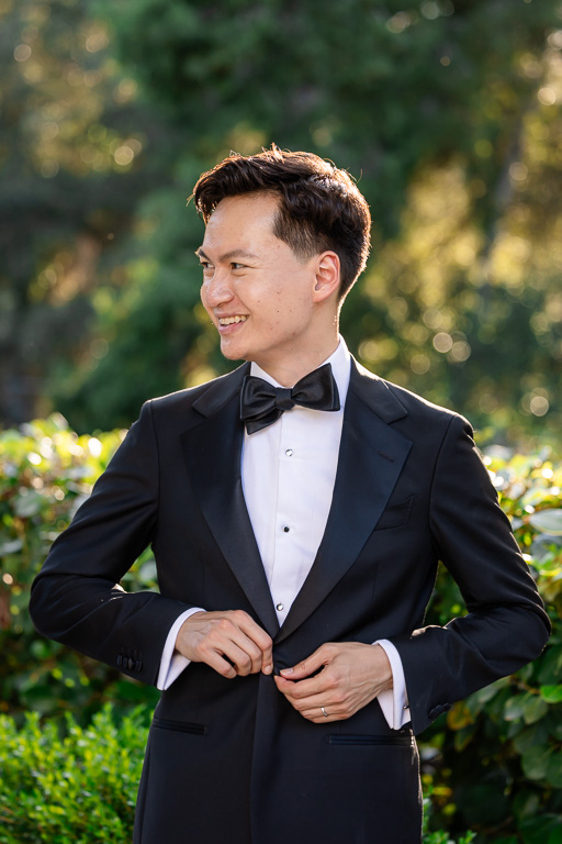 the groom during wedding prep buttoning his jacket