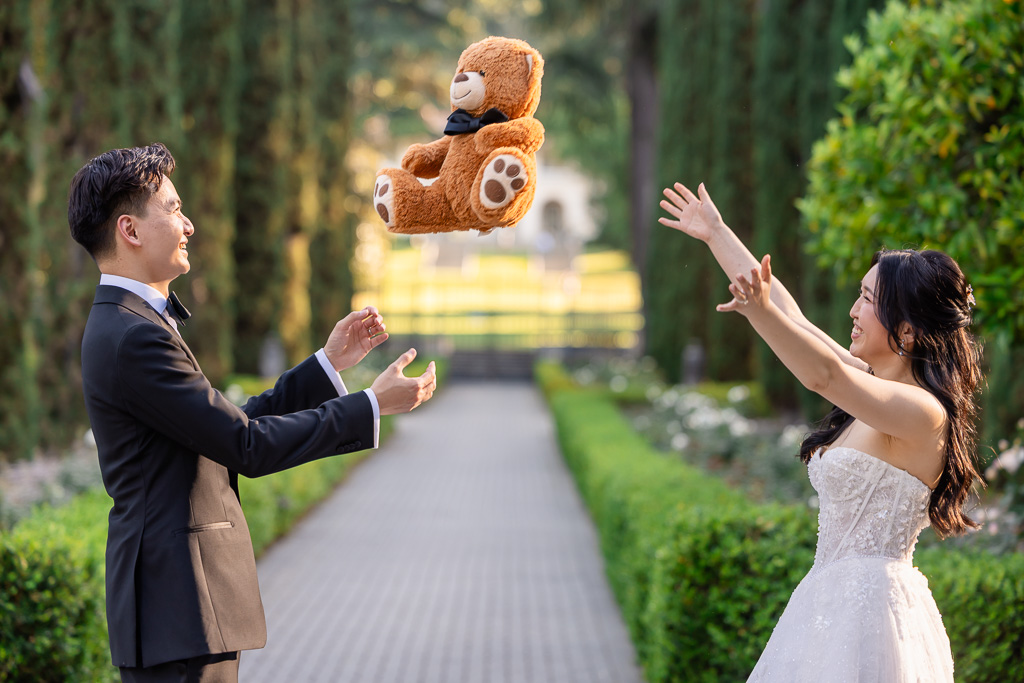 playful photo of bride and groom tossing a stuffed eddy bear between them