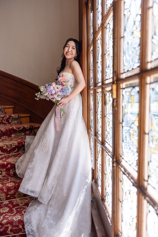 bride solo on staircase near huge stained glass window