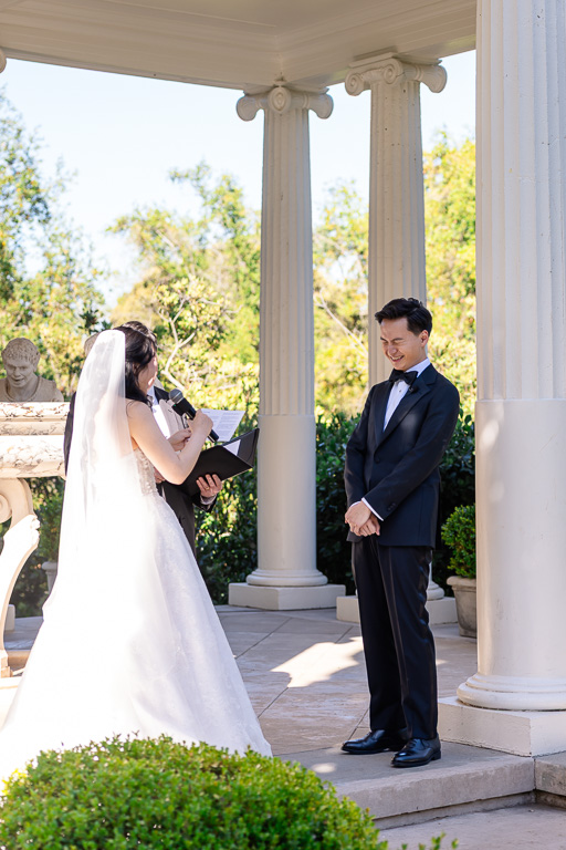groom smiling at his bride as she says her vows