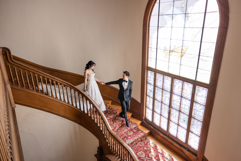 wide dramatic photo of bride and groom walking down the spiral staircase of Villa Montalvo