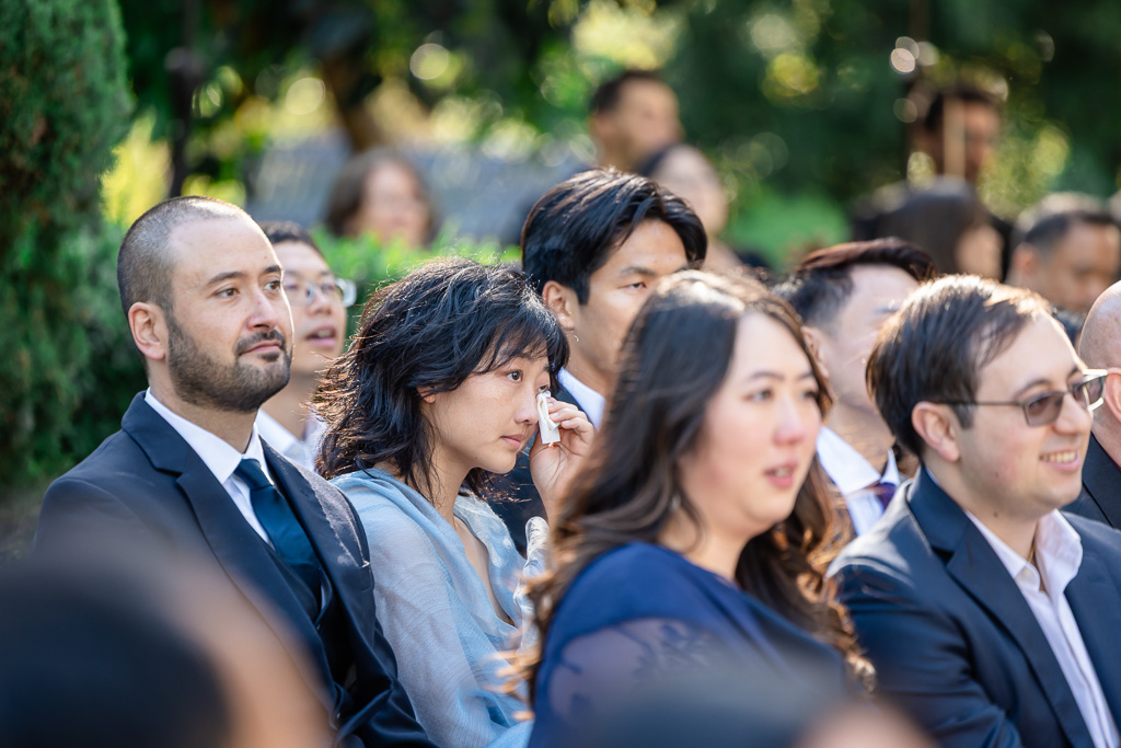wedding guest wiping tears during an emotional moment of the vow exchange