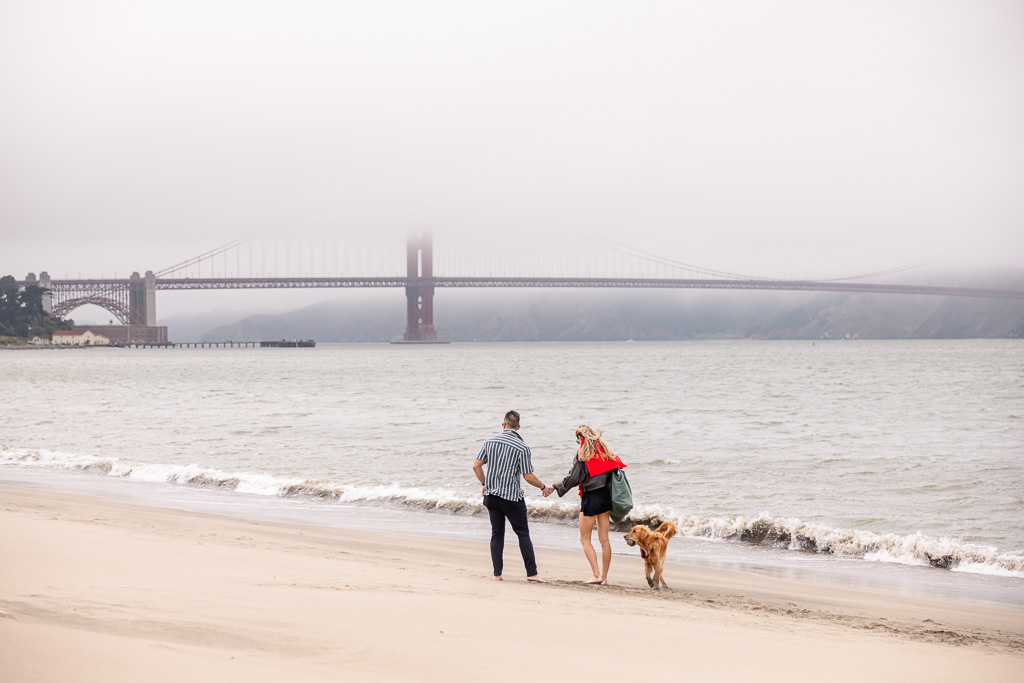 couple walking their dog on a foggy day at Crissy Field beach