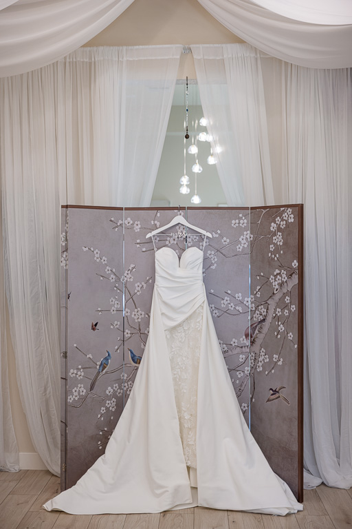 wedding dress hanging on a floral backdrop