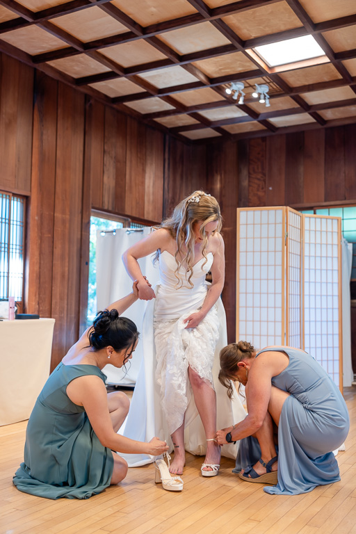 bridesmaids helping the bride get her shoes on
