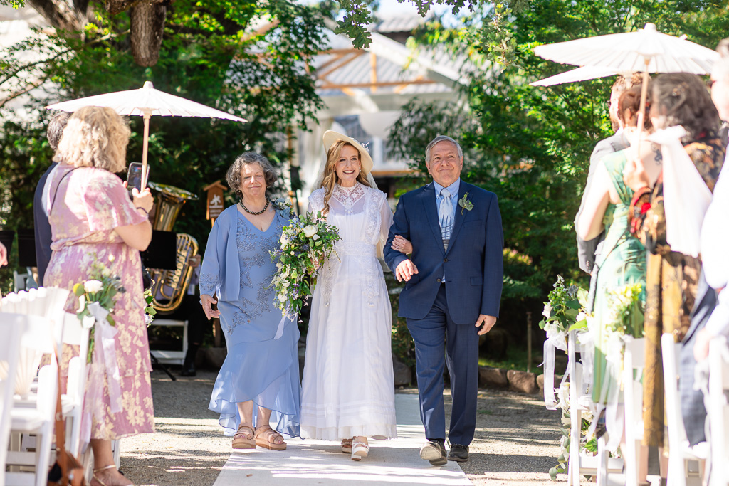 bride wearing a passed-down vintage dress walking down the aisle with her parents