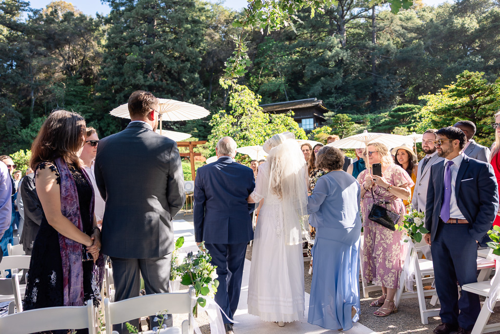 bride and parents walking towards the arbor