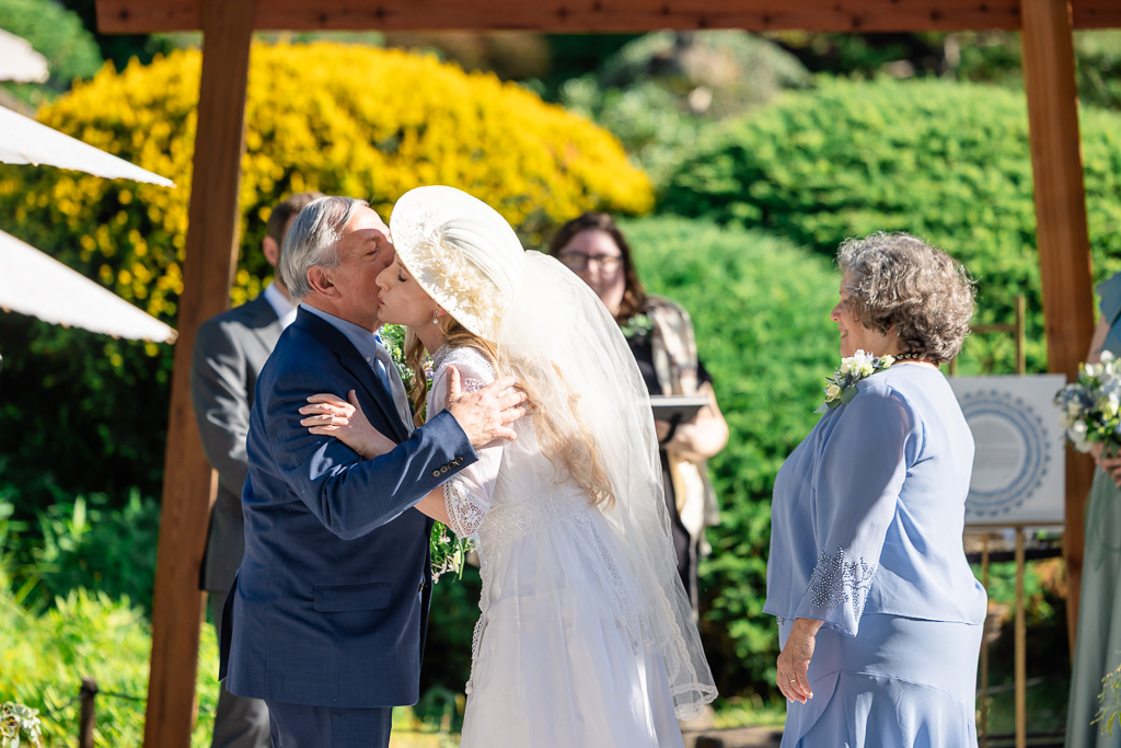 bride and dad hugging and kissing at the end of the aisle