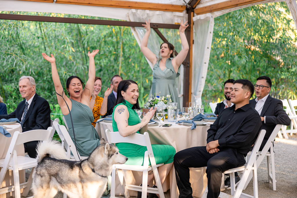 guests and bridesmaids cheering at the reception table