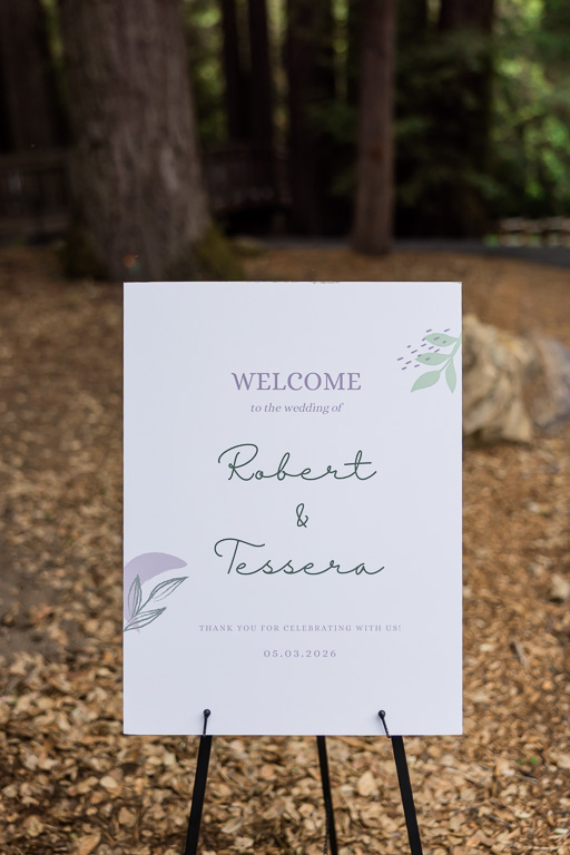 white wedding welcome sign in a wooded setting