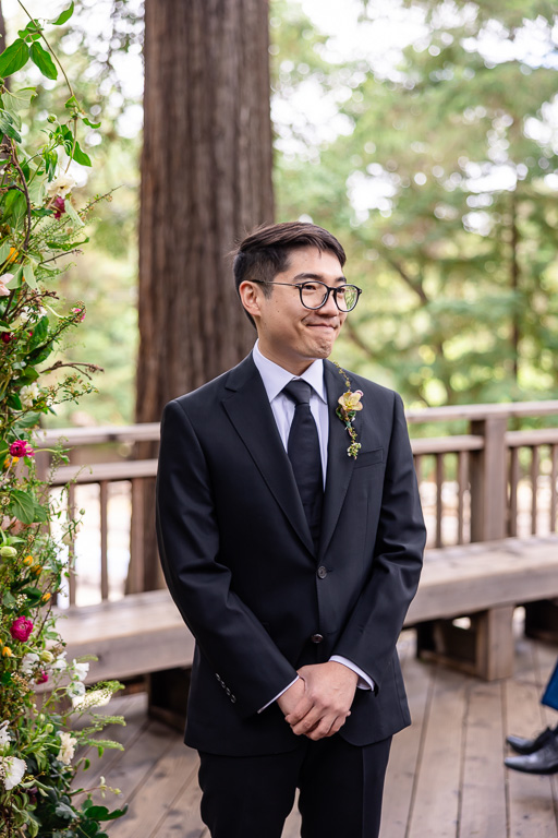 groom looking down the aisle as his bride approaches