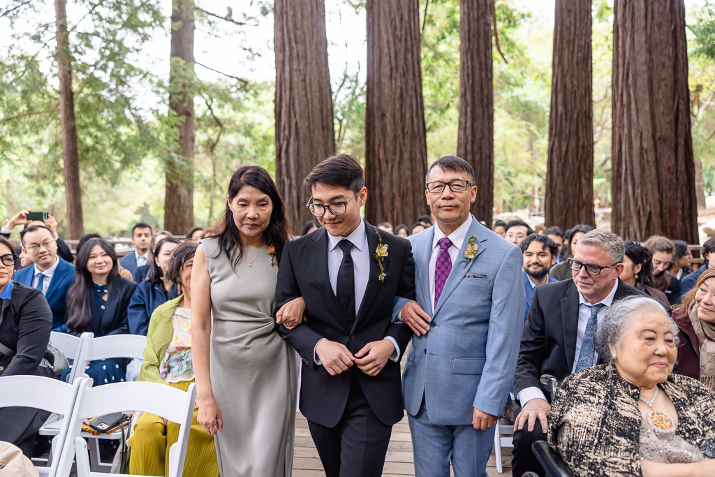 groom walking up the aisle with his parents on each side