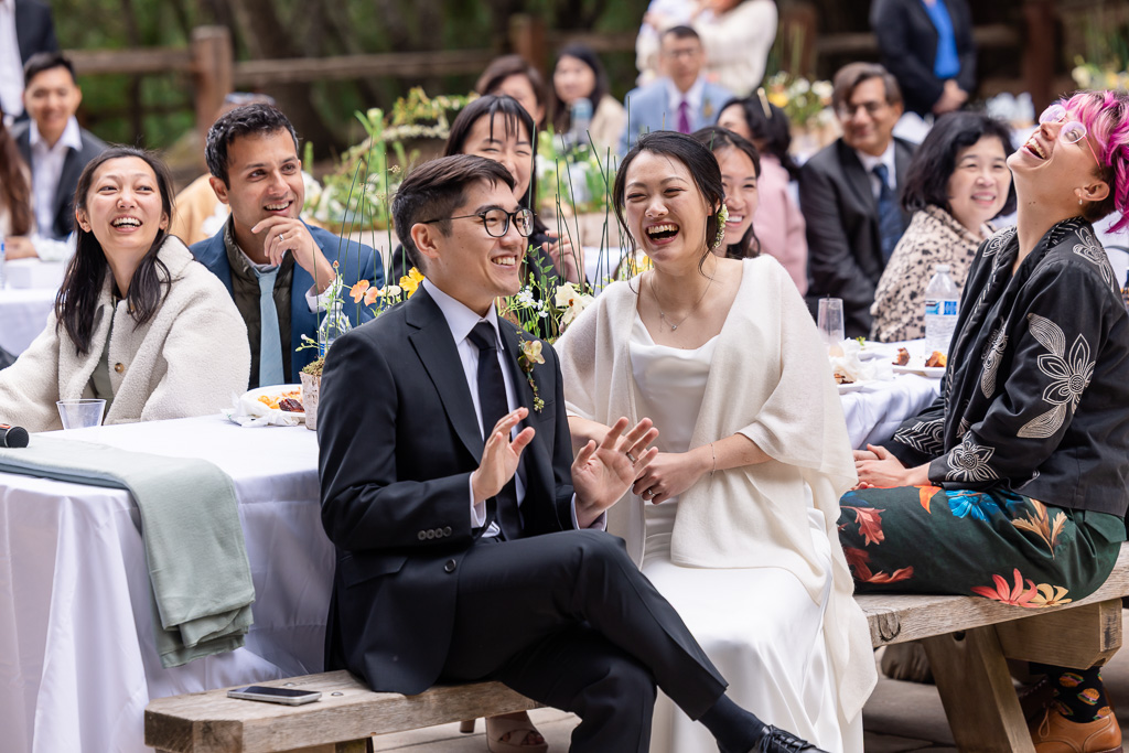 the newlyweds laughing at a wedding dinner toast