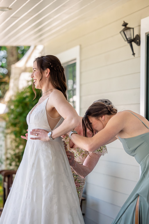 bridesmaid helping bride button up her dress