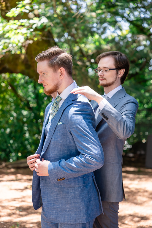 best man prepping the groom and putting on his suit