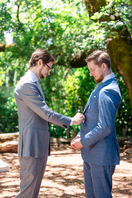 best man helping groom button up suit
