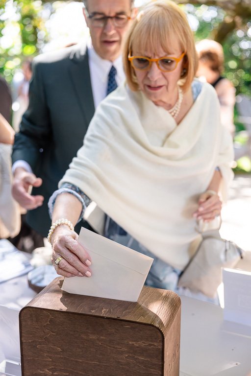 an elderly wedding guest dropping her card into the card box