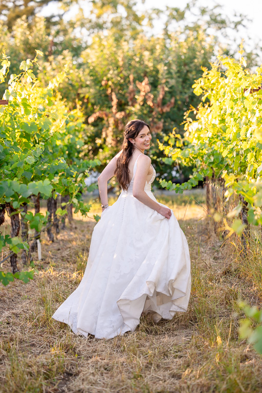 cute candid shot of bride in her wedding dress running through vineyards