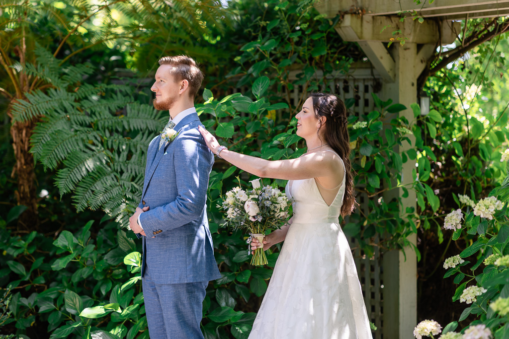 bride tapping groom on the shoulder for first look≤