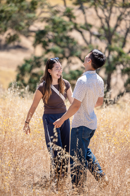 couple laughing and sharing a moment together in golden hills