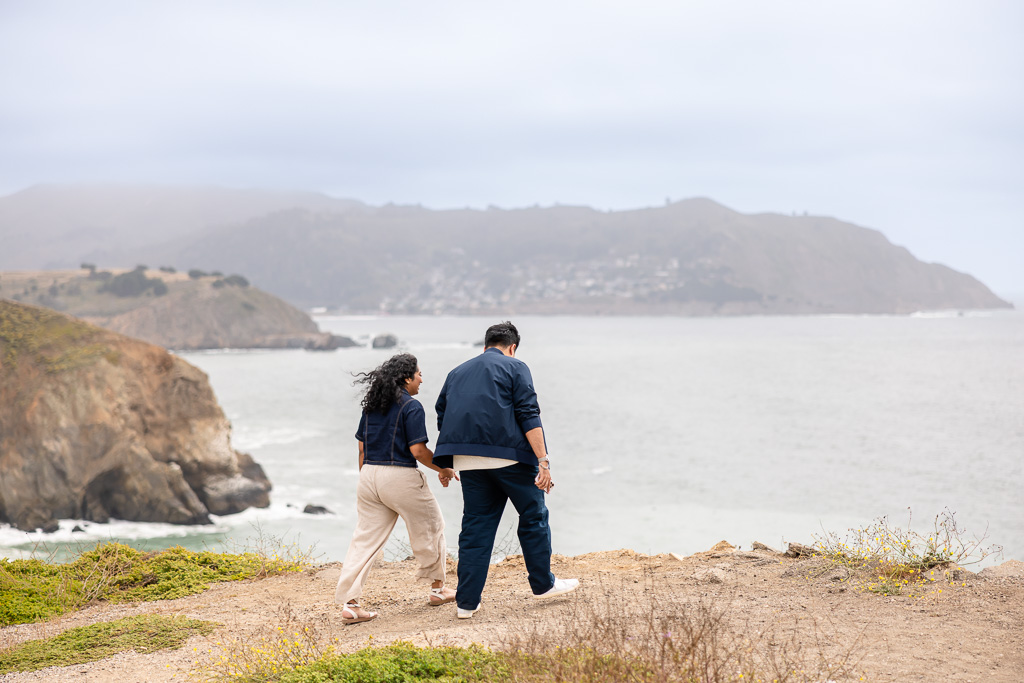 couple walking towards coastal cliffside viewpoint