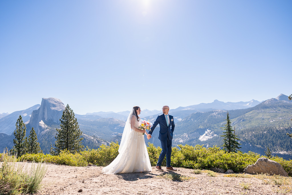 bride and groom walking along Glacier Point overlook