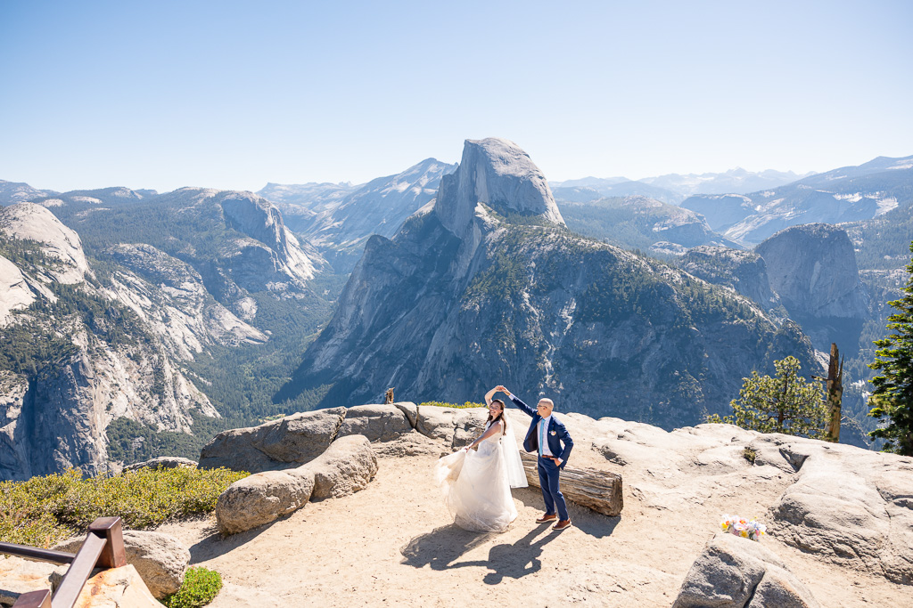 bride & groom in wedding attire dancing and spinning at Glacier Point overlook