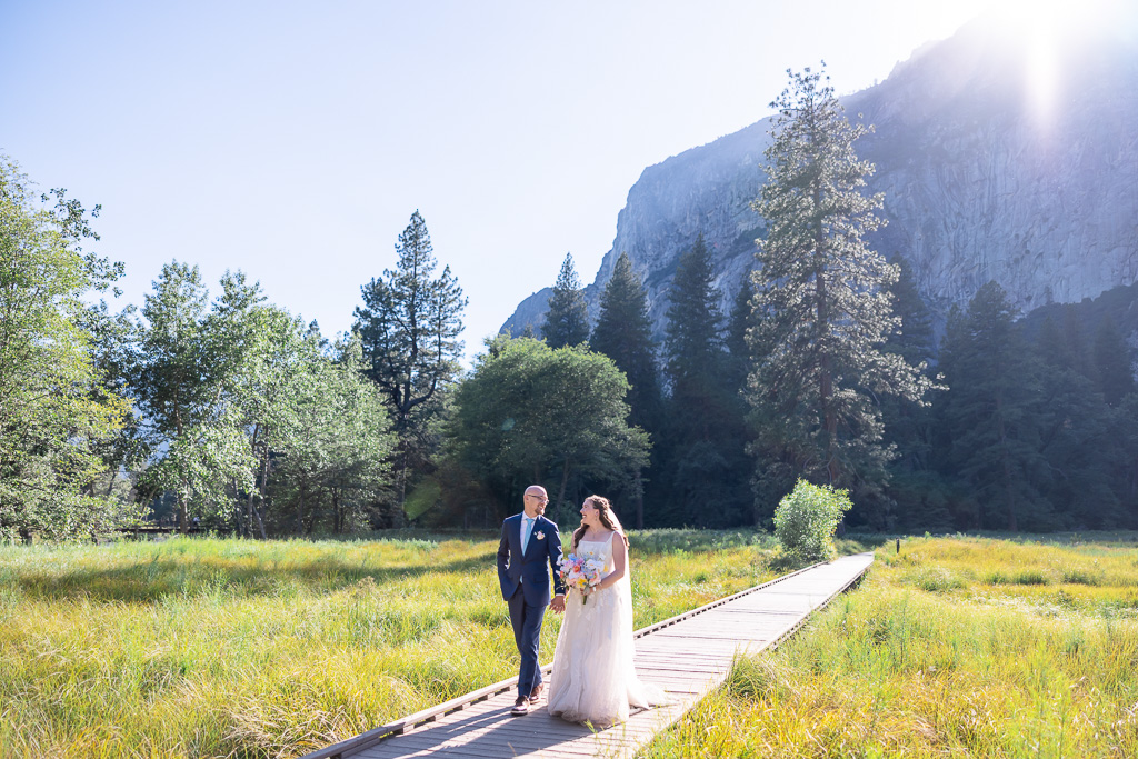 bride & groom walking along the wooden boardwalk at Cook’s Meadow