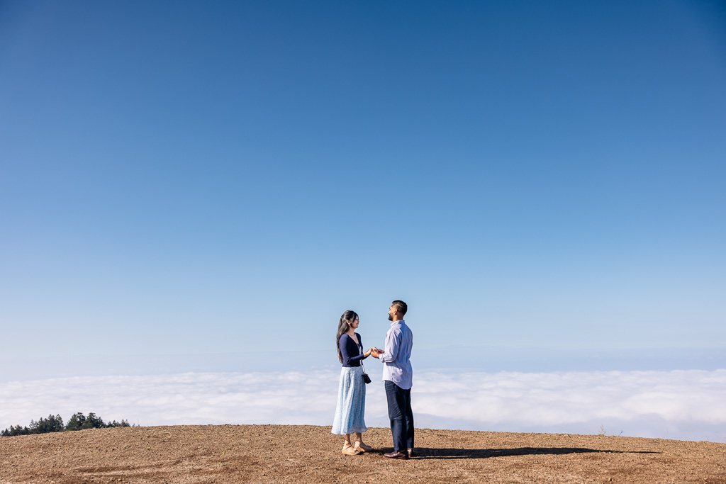 couple standing facing each other with a sea of fog behind them