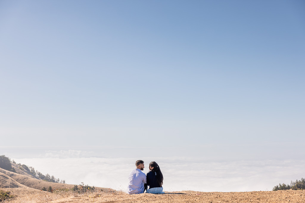 engagement photos sitting down facing a wall of fog