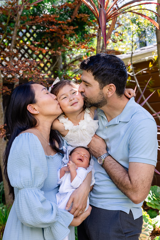 parents kissing newborn child