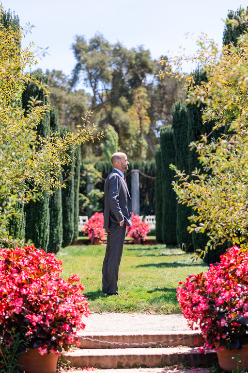 groom standing in a garden aisle waiting for first look