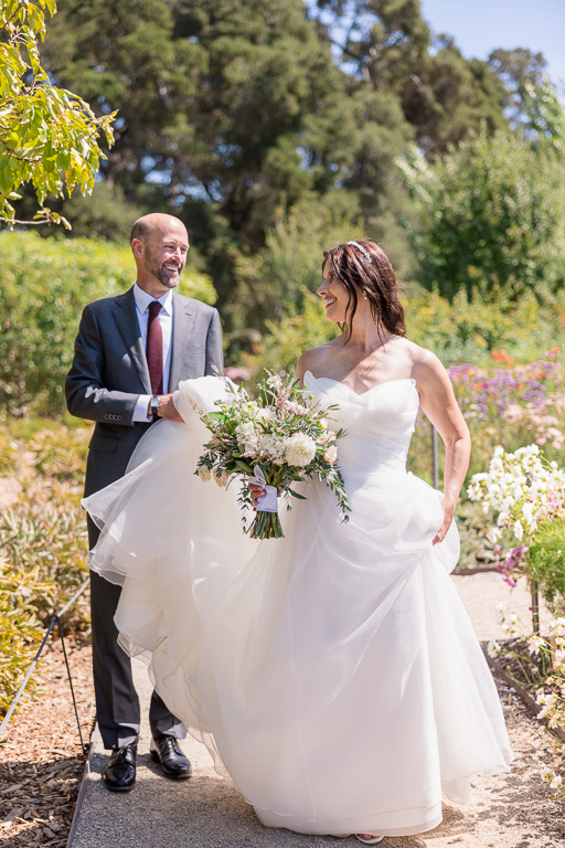 groom with bride walking through a narrow garden path