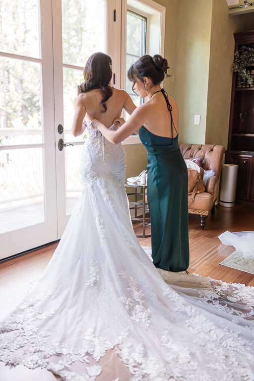 sister helping bride with her dress