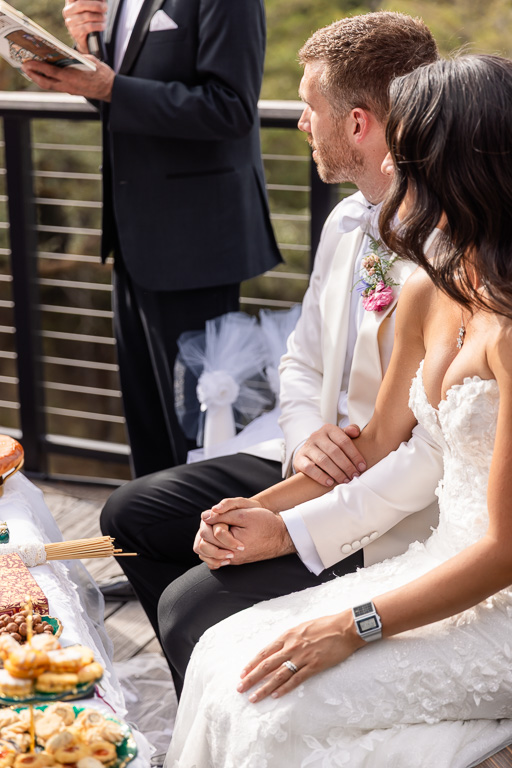 bride and groom seated and holding hands